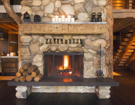 Fireplace made of stone inside a cabin with multiple floors.